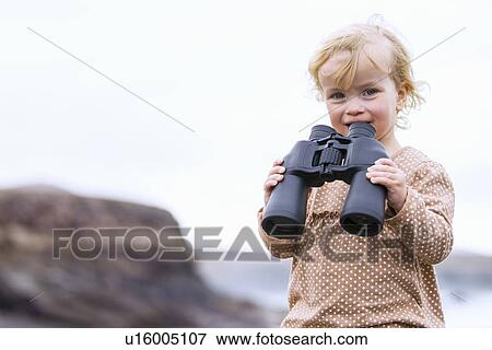 Stock Photo - Toddler girl using binoculars on beach. Fotosearch