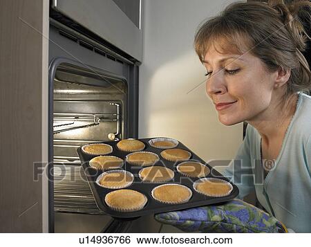 Woman baking cupcakes in kitchen View Large Photo Image Stock Photograph - Woman baking cupcakes in kitchen. Fotosearch