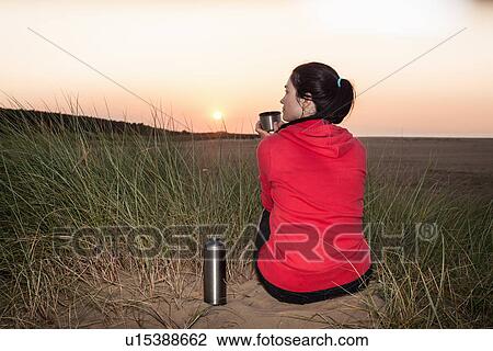 Woman drinking from thermos on beach View Large Photo Image Stock Image - Woman drinking from thermos on beach. Fotosearch