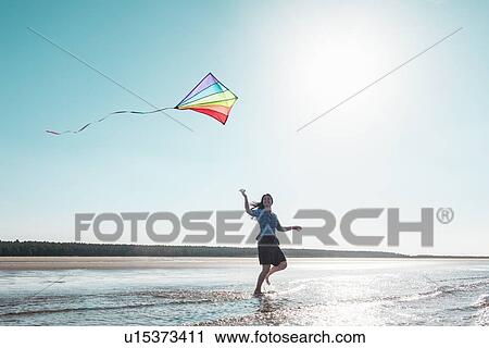 Woman flying kite on beach View Large Photo Image Stock Image - Woman flying kite on beach. Fotosearch