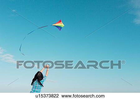 Stock Image - Woman flying kite outdoors. Fotosearch