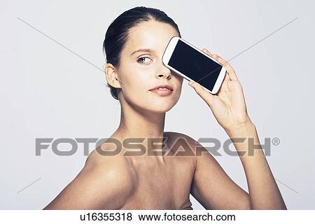 Woman holding cell phone by face View Large Photo Image Stock Photo - Woman holding cell phone by face. Fotosearch