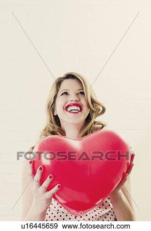 Woman holding heart shaped balloon View Large Photo Image Stock Photo - Woman holding heart shaped balloon. Fotosearch