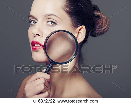 Woman holding magnifying glass to face View Large Photo Image Stock Image - Woman holding magnifying glass to face. Fotosearch