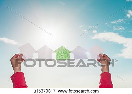 Stock Photo - Woman holding paper houses in sky. Fotosearch