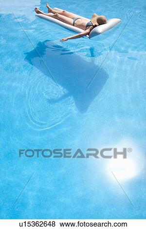 Stock Photo - Woman laying on raft in swimming pool. Fotosearch
