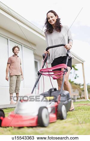 Stock Image - Woman mowing green lawn. Fotosearch