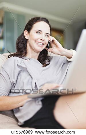 Woman on cell phone using laptop View Large Photo Image Stock Photo - Woman on cell phone using laptop. Fotosearch