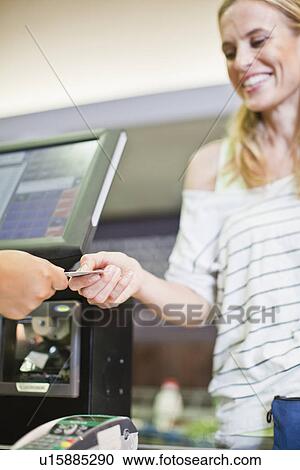 Stock Image - Woman paying with credit card in store. Fotosearch