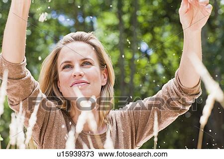 Stock Image - Woman playing with plants in park. Fotosearch