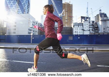 Woman running on city street View Large Photo Image Stock Photograph - Woman running on city street. Fotosearch