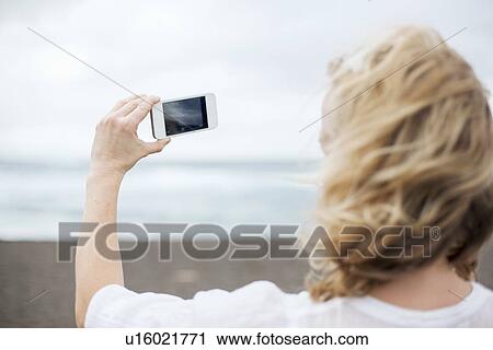 Woman taking cell phone picture on beach View Large Photo Image Stock Image - Woman taking cell phone picture on beach. Fotosearch
