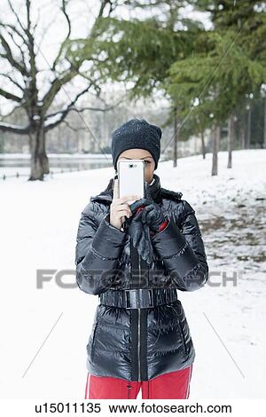 Stock Photography - Woman taking picture in snowy field. Fotosearch