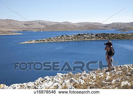 Stock Photograph - Woman taking pictures of landscape. Fotosearch