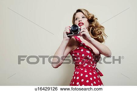 Stock Photograph - Woman taking pictures with vintage camera. Fotosearch