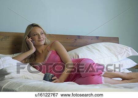 Stock Photo - Woman talking on phone in bed. Fotosearch