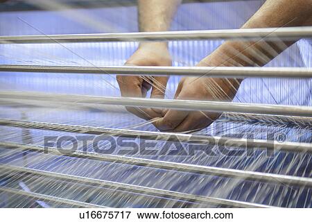 Stock Photo - Worker adjusting threads on loom. Fotosearch