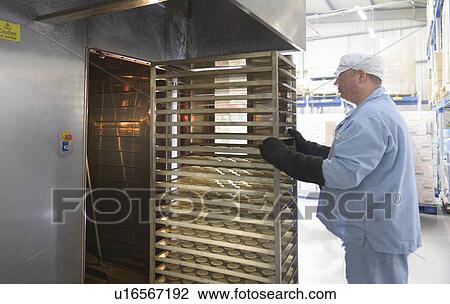 Stock Image - Worker baking biscuits in factory. Fotosearch