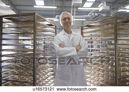 Stock Image - Worker baking biscuits in factory. Fotosearch