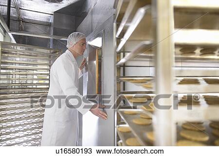 Stock Image - Worker baking biscuits in factory. Fotosearch