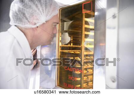 Stock Image - Worker baking biscuits in factory. Fotosearch