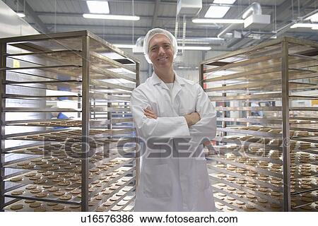 Stock Photograph - Worker baking biscuits in factory. Fotosearch