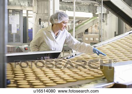 Stock Image - Worker checking production line in factory. Fotosearch