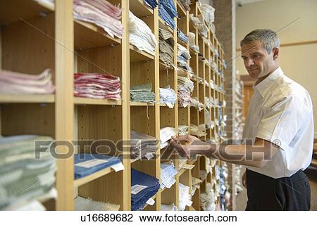 Stock Image - Worker examining fabric in textile mill. Fotosearch