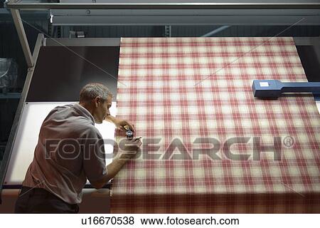 Worker examining fabric in textile mill View Large Photo Image Stock Photo - Worker examining fabric in textile mill. Fotosearch