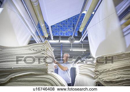 Worker examining fabric in textile mill View Large Photo Image Stock Photo - Worker examining fabric in textile mill. Fotosearch