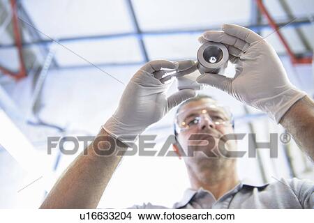Worker examining steel part in factory View Large Photo Image Picture - Worker examining steel part in factory. Fotosearch
