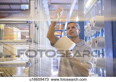 Worker examining thread in textile mill View Large Photo Image Stock Image - Worker examining thread in textile mill. Fotosearch