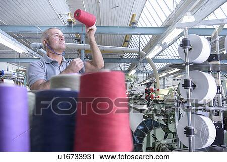 Worker examining thread in textile mill View Large Photo Image Stock Image - Worker examining thread in textile mill. Fotosearch