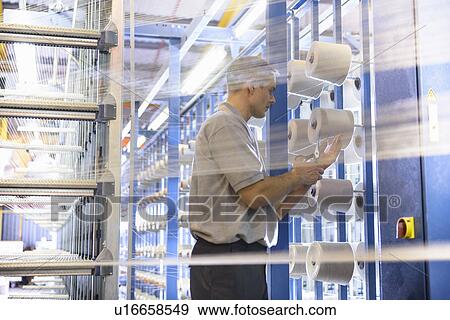 Stock Photo - Worker examining thread in textile mill. Fotosearch