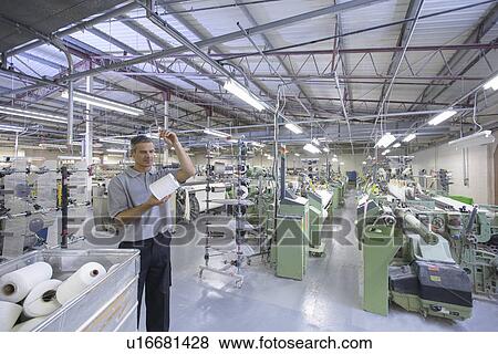Stock Photo - Worker examining thread in textile mill. Fotosearch