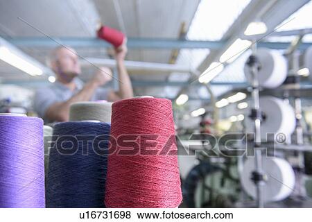Stock Photo - Worker examining thread in textile mill. Fotosearch