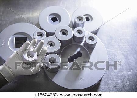 Stock Image - Worker holding steel part in factory. Fotosearch