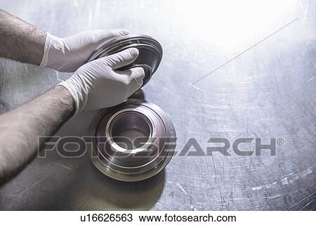 Worker holding steel part in factory View Large Photo Image Stock Image - Worker holding steel part in factory. Fotosearch