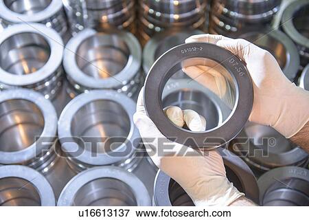 Stock Photo - Worker holding steel ring in factory. Fotosearch