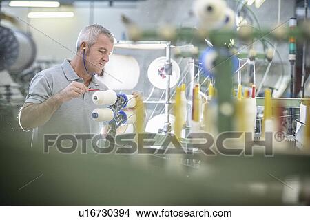 Picture - Worker using loom in textile mill. Fotosearch
