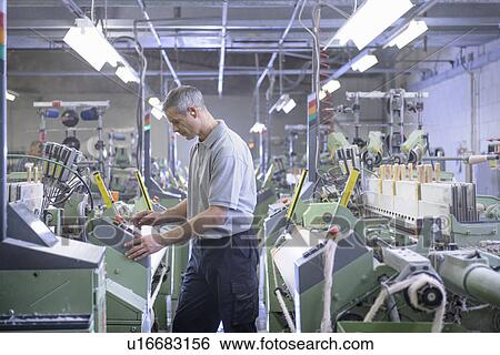 Stock Photograph - Worker using loom in textile mill. Fotosearch