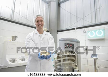 Stock Image - Worker with handful of oats in factory. Fotosearch
