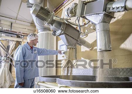Stock Image - Worker with machinery in biscuit factory. Fotosearch
