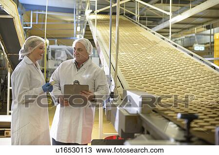 Stock Image - Workers talking in biscuit factory. Fotosearch