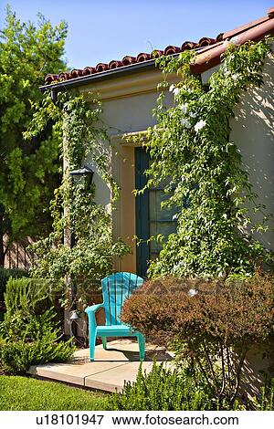 A lonely blue chair outside a house surrounded by plants View Large Photo Image Stock Photo - A lonely blue chair outside a house surrounded by plants. Fotosearch