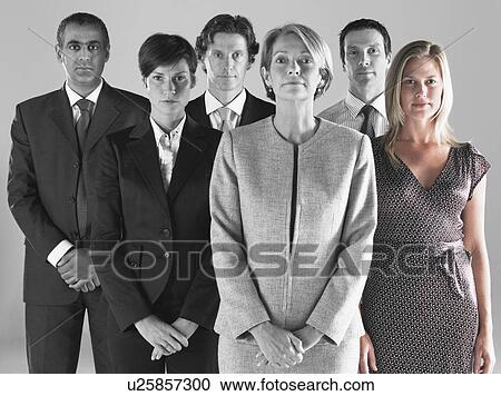 Stock Image - Ambitious businesswoman with team of professionals against gray background. Fotosearch