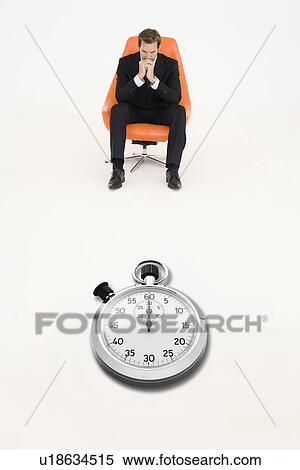 Anxious businessman sitting on chair with stopwatch in front of him representing loss of time View Large Photo Image Stock Photography - Anxious businessman sitting on chair with stopwatch in front of him representing loss of time. Fotosearch