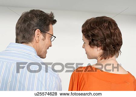 Back view of couple looking at each other against white wall View Large Photo Image Stock Photo - Back view of couple looking at each other against white wall. Fotosearch