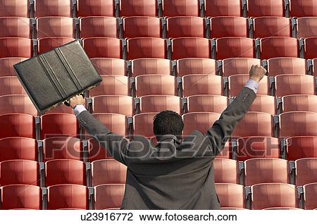 Back view of victorious businessman with briefcase facing rows of red seats at stadium View Large Photo Image Stock Image - Back view of victorious businessman with briefcase facing rows of red seats at stadium. Fotosearch