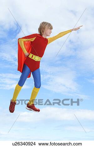 Picture - Boy dressed as superhero flying against cloudy sky. Fotosearch